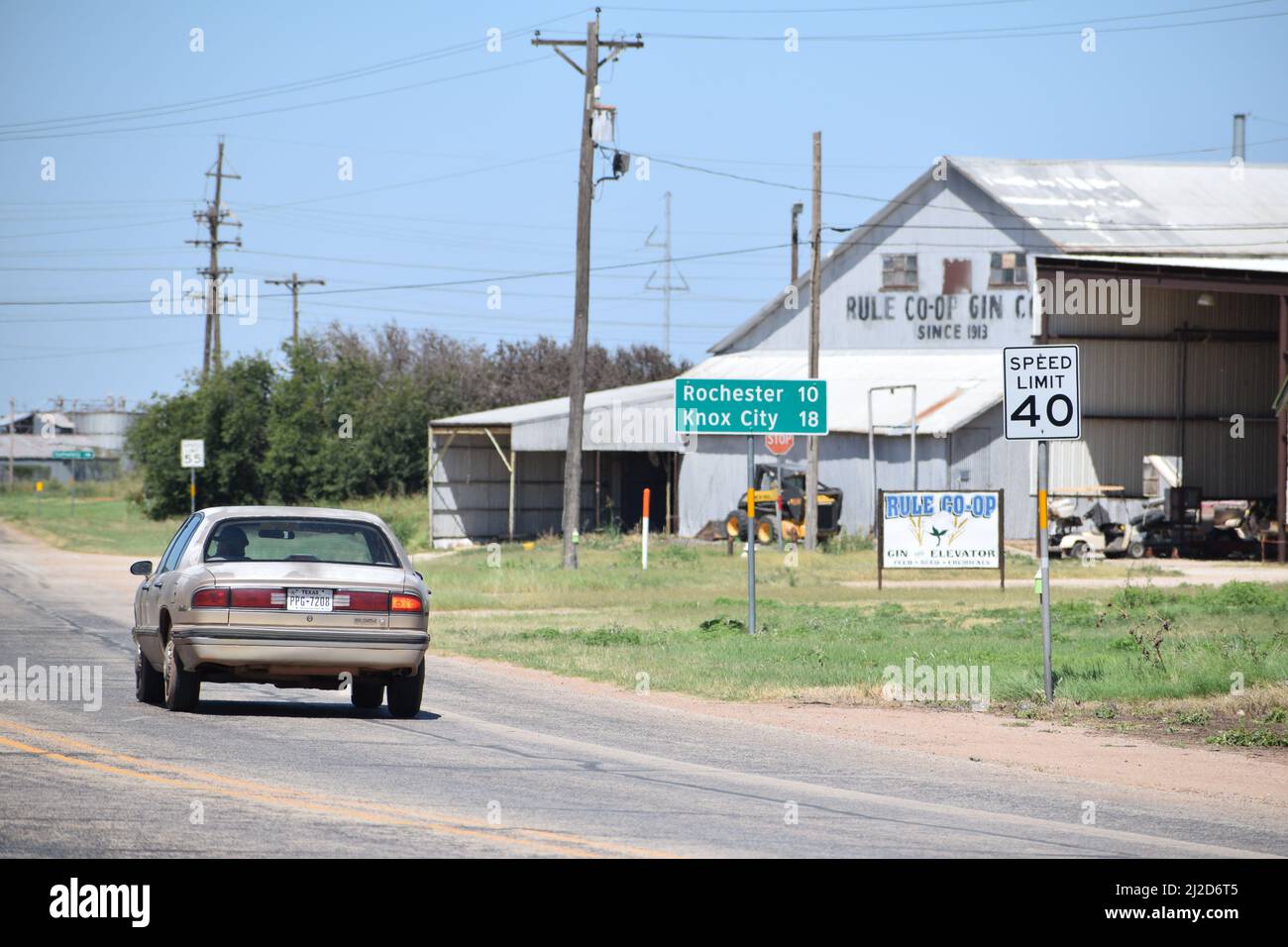 Uomo in un Buick che guida lungo una strada rurale in Rule Texas passato il Rule Cotton Gin - 2021 agosto Foto Stock
