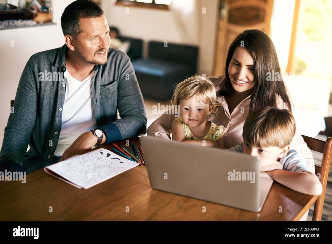 Gioca, divertiti e impara tutto in uno. Girato di un adorabile fratello e sorella utilizzando un computer portatile con la madre a casa. Foto Stock