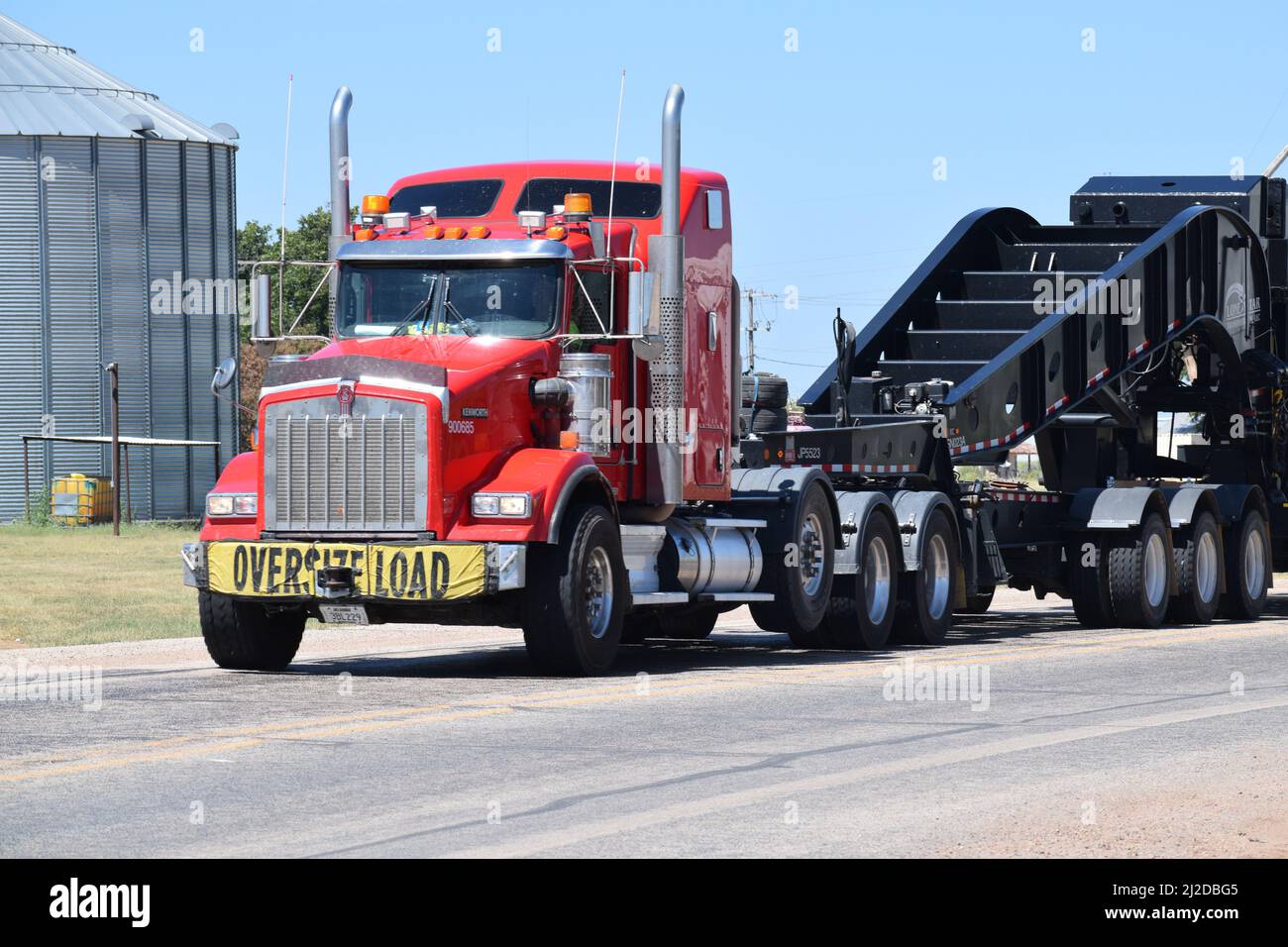 Semi-camion rosso che tira un carico sovradimensionato lungo un'autostrada a Rule Texas - Agosto 2021 Foto Stock