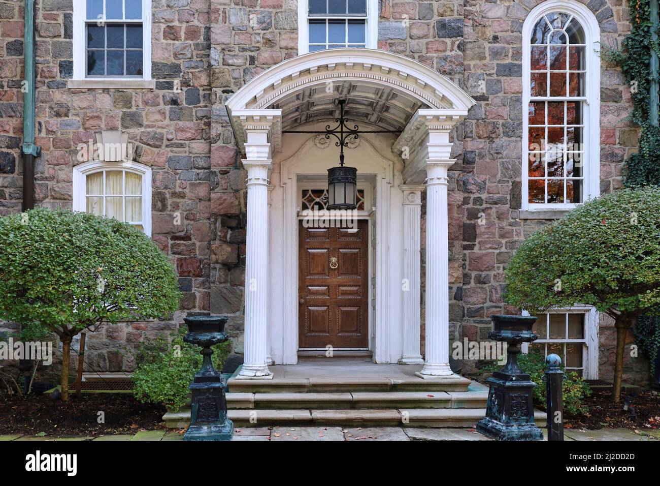 Antica casa in pietra con ingresso portico ed elegante porta frontale in legno Foto Stock