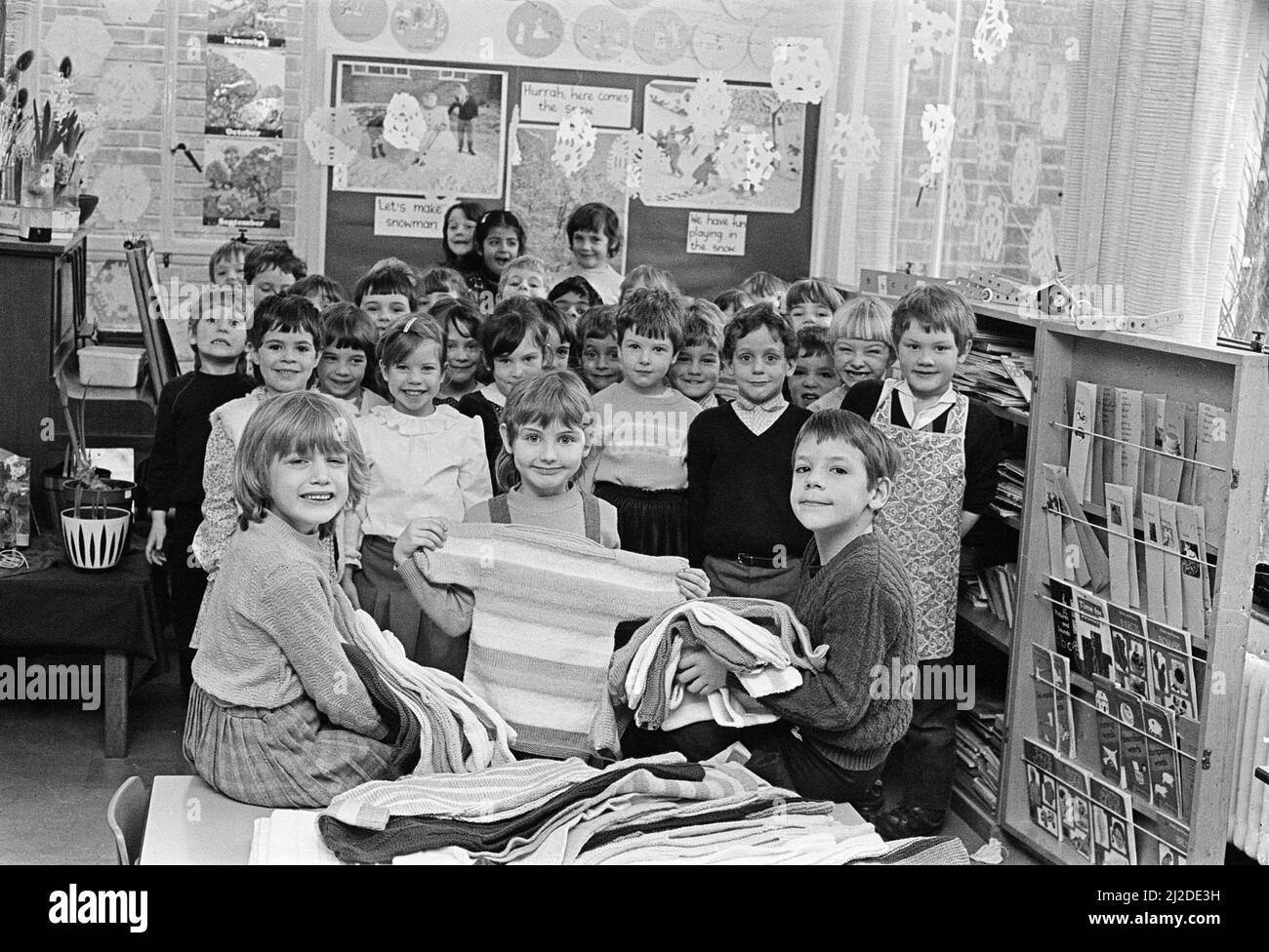 I bambini alla scuola di lattanti di Lindley CoFe esaminano alcuni del lavoro di handiwork degli insegnanti e delle madri che, con i membri e le madri delle guide metodiste e dei brownies di Lindley hanno lavorato a maglia 100 jumpers per i bambini in Etiopia. 7th febbraio 1985. Foto Stock