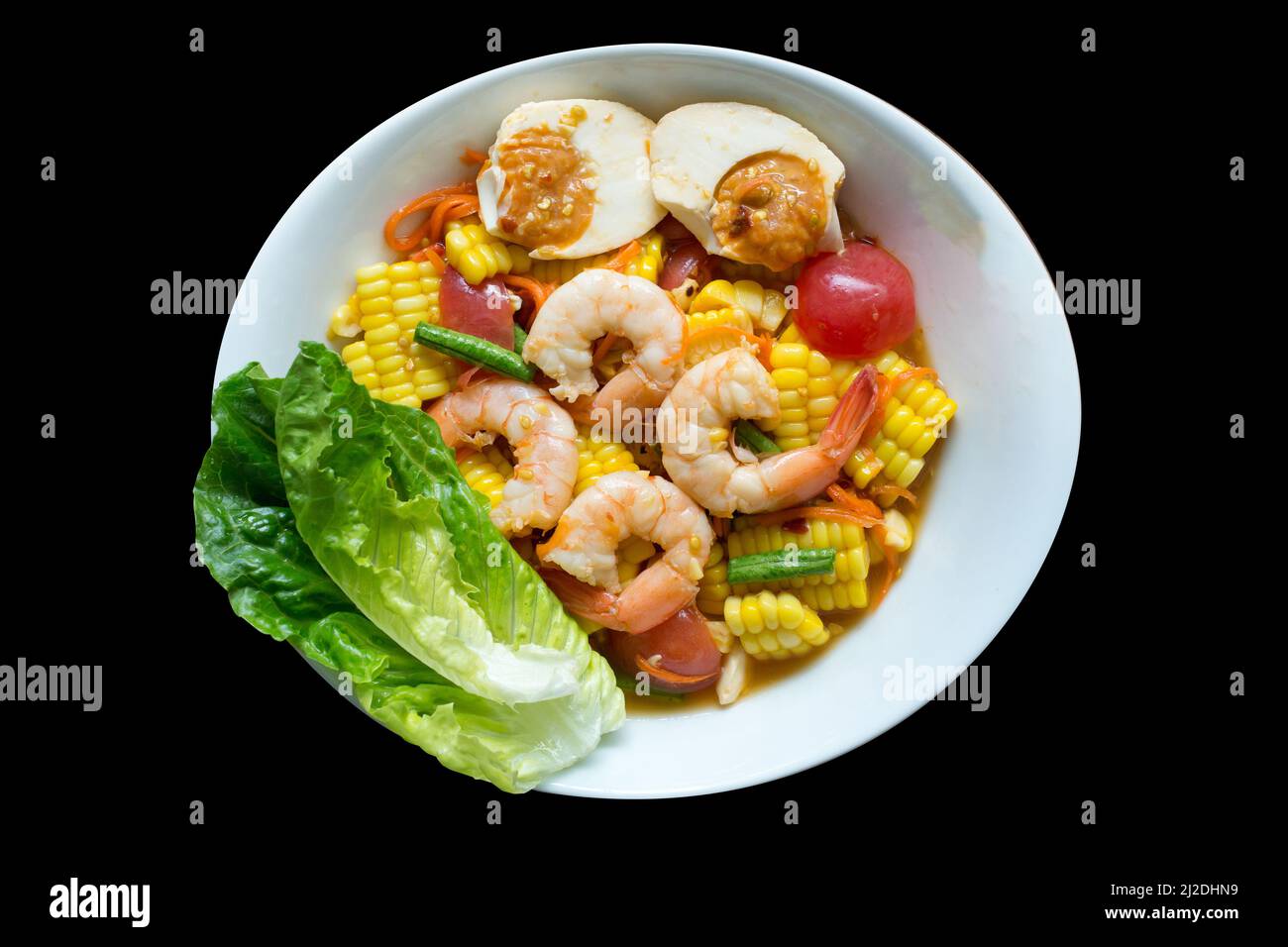 Vista dall'alto di granoturco piccante e insalata di uova salate con lattuga di quercia verde su nero isolato. Foto Stock