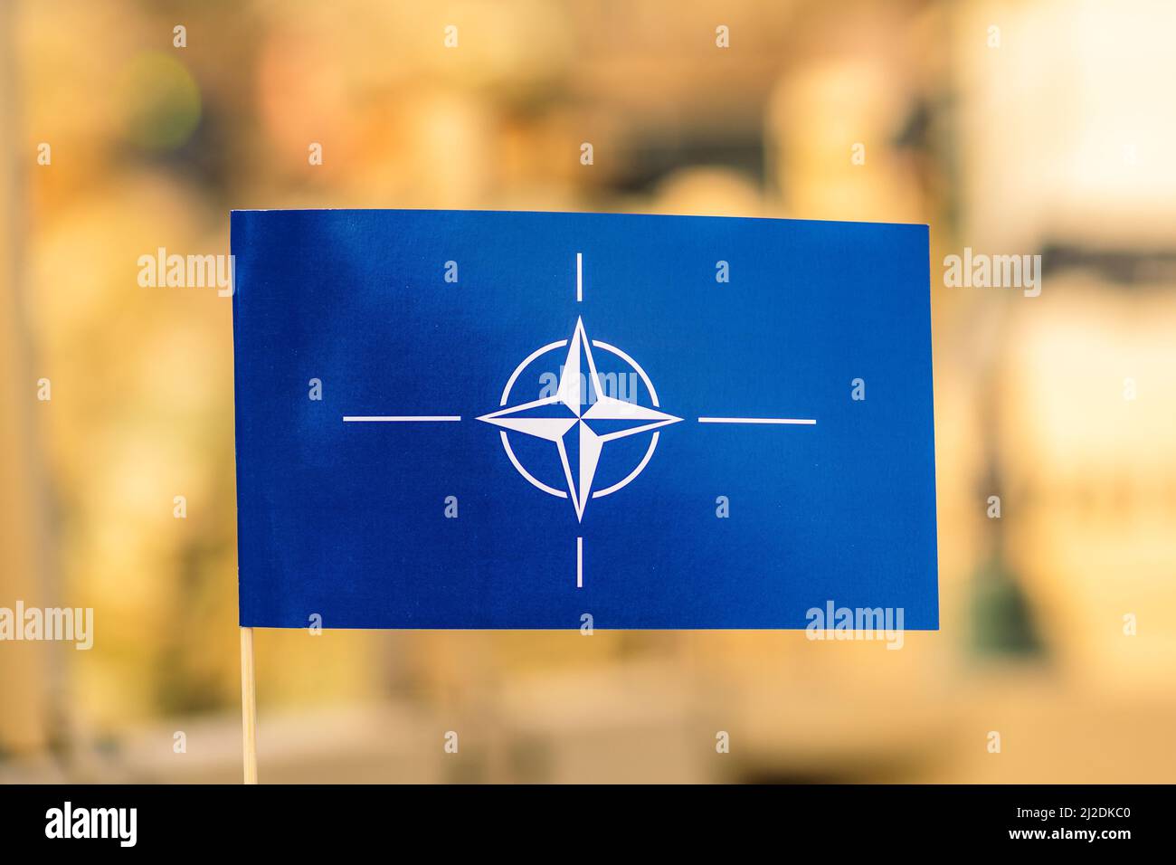 Bandiera e simbolo della NATO, Organizzazione del Trattato del Nord Atlantico, unità di integrazione della forza con background fuori fuoco Foto Stock