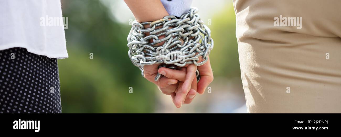 Vista posteriore del giovane la mano legata con catena di metallo in corrispondenza all'aperto Foto Stock