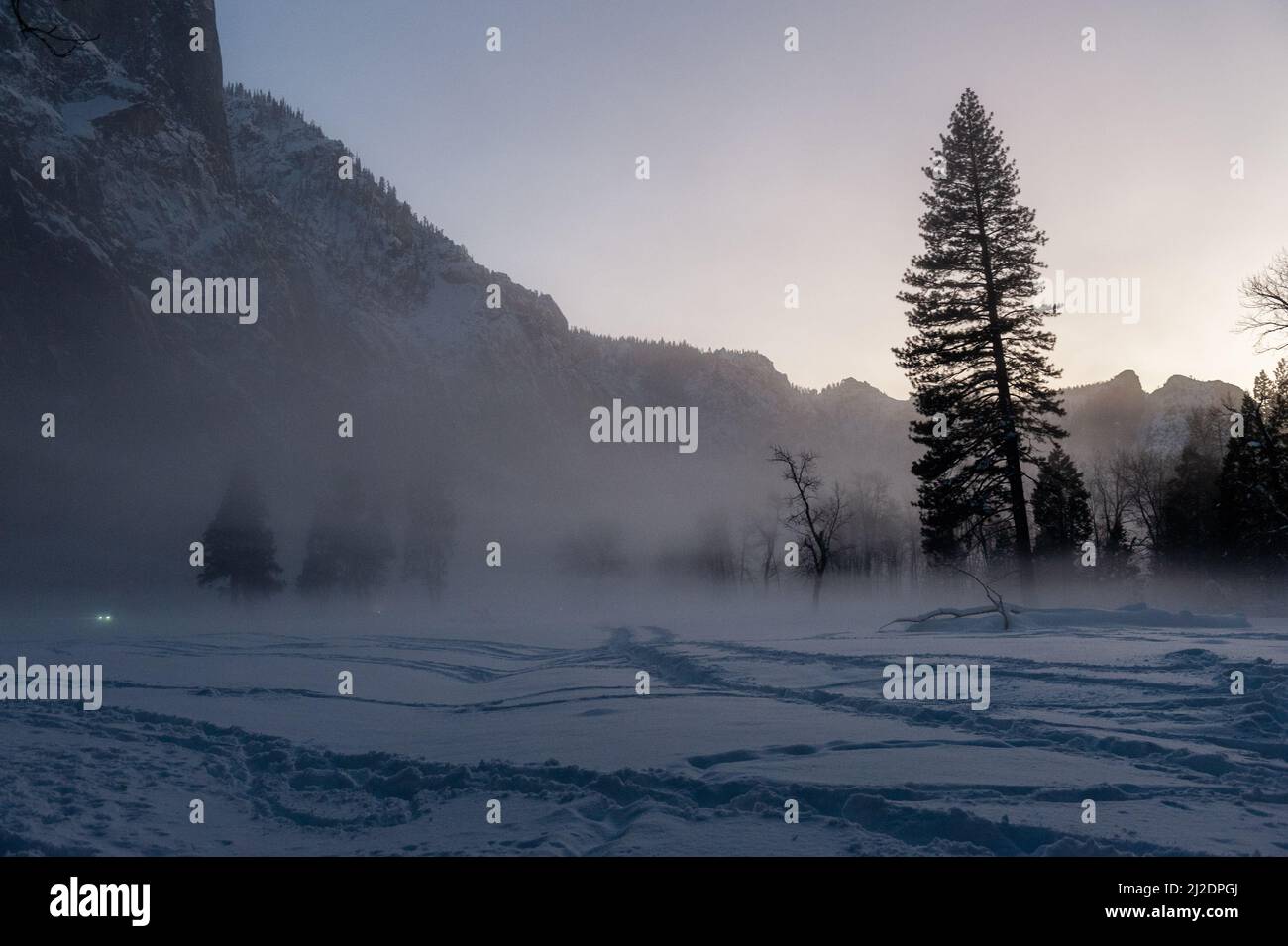 La valle di Yosemite è circondata da un sottile strato di nebbia che si estende sul fiume merced, fornendo un'atmosfera inquietante intorno al tramonto. Foto Stock