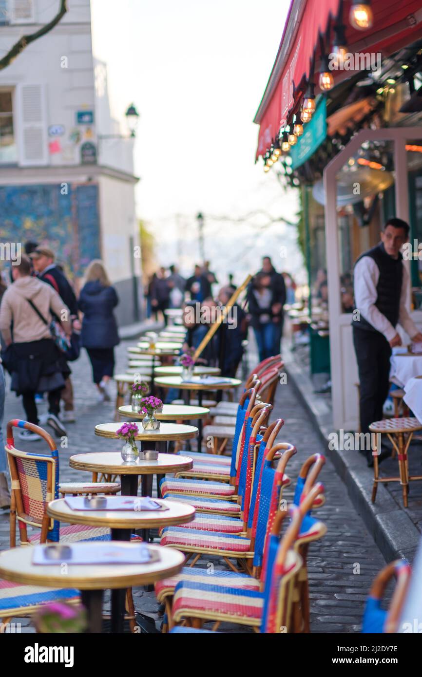 Parigi, Francia - 22 marzo 2022 : i turisti si godono di bevande all'aperto nella pittoresca zona di Montmartre e sono serviti da un cameriere francese Foto Stock