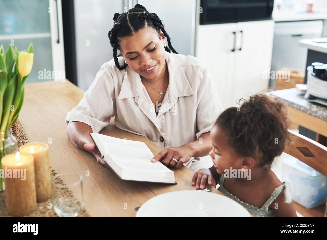 Non sono un insegnante, ma un risveglio. Shot di una madre che insegna a sua figlia la bibbia a casa. Foto Stock