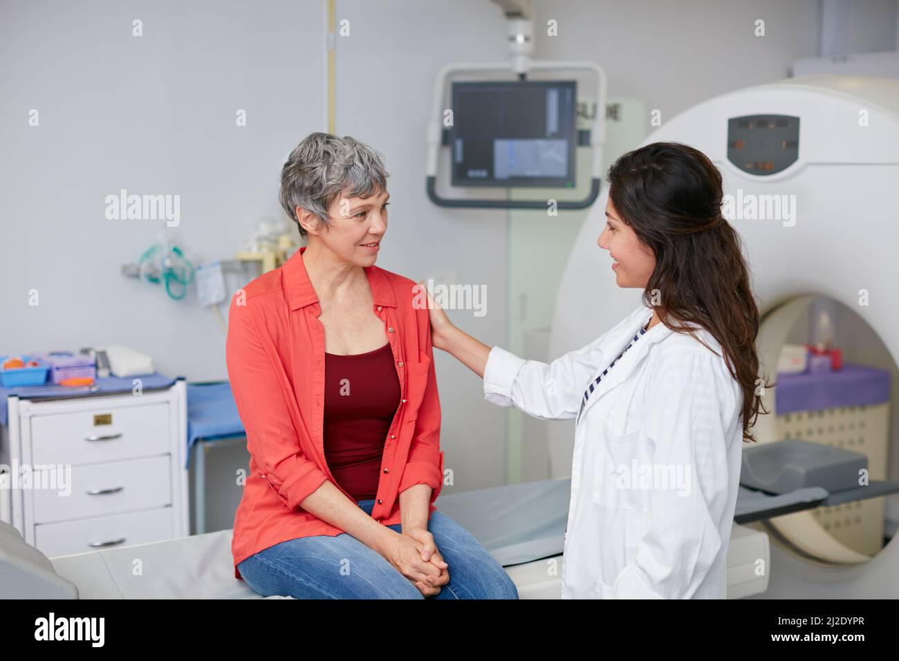 Abbiamo i risultati della tua scansione. Scatto di una donna matura che è confortata da un medico prima e MRI scan. Foto Stock