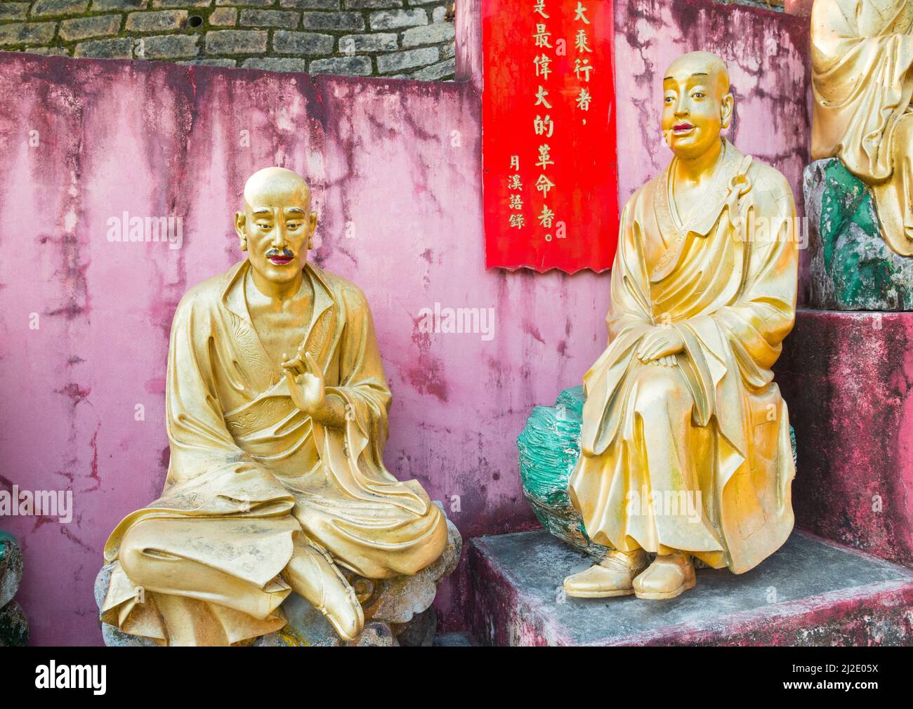 Belle statue di buddha in fila. Sculture religiose dorate che rappresentano un vecchio buddhisti/monaci. Diecimila Buddha Monastero, Hong Kong, Asia Foto Stock