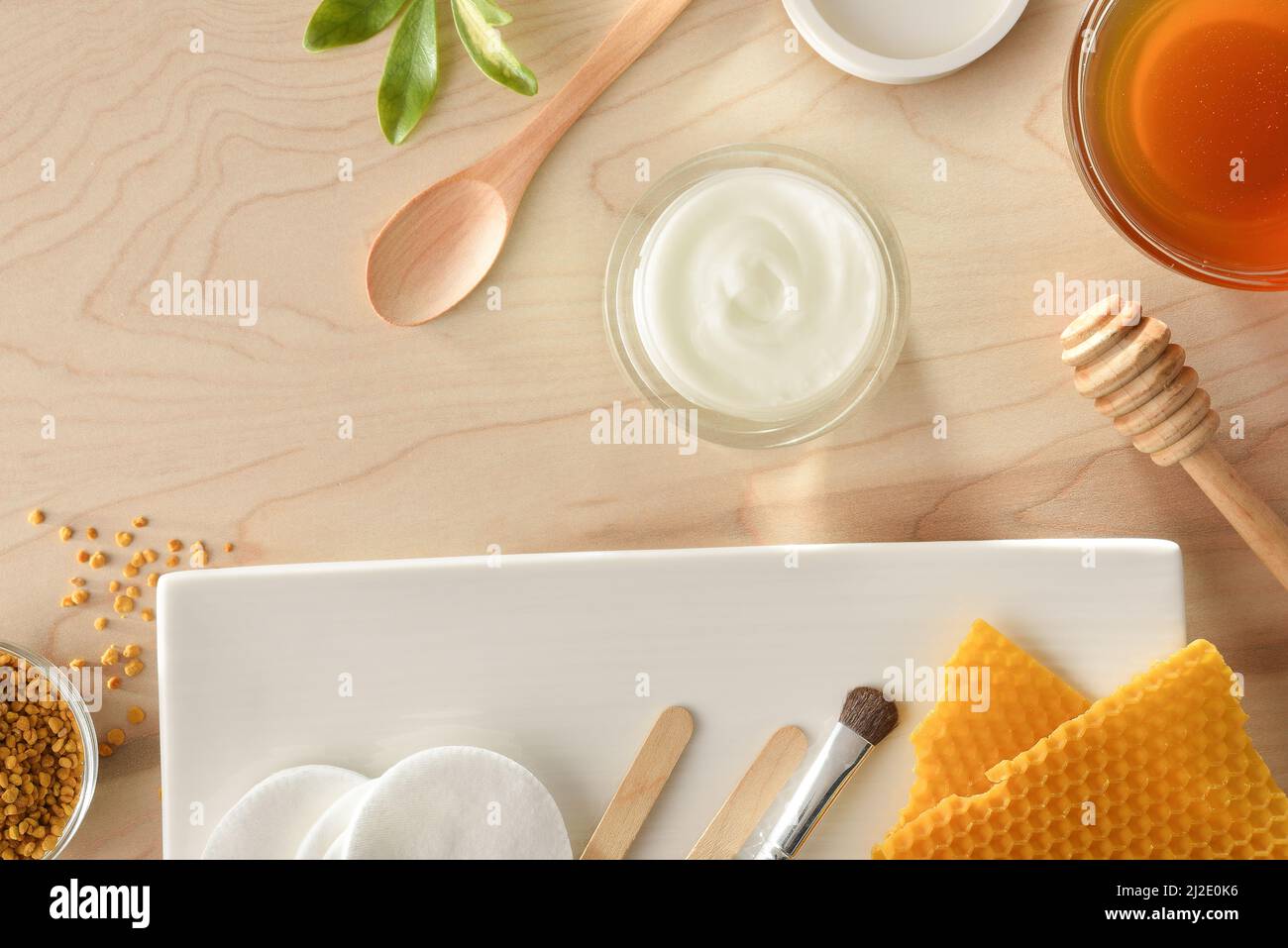 Cosmetici con estratti di miele con utensili su tavola di legno. Composizione orizzontale. Vista dall'alto. Foto Stock