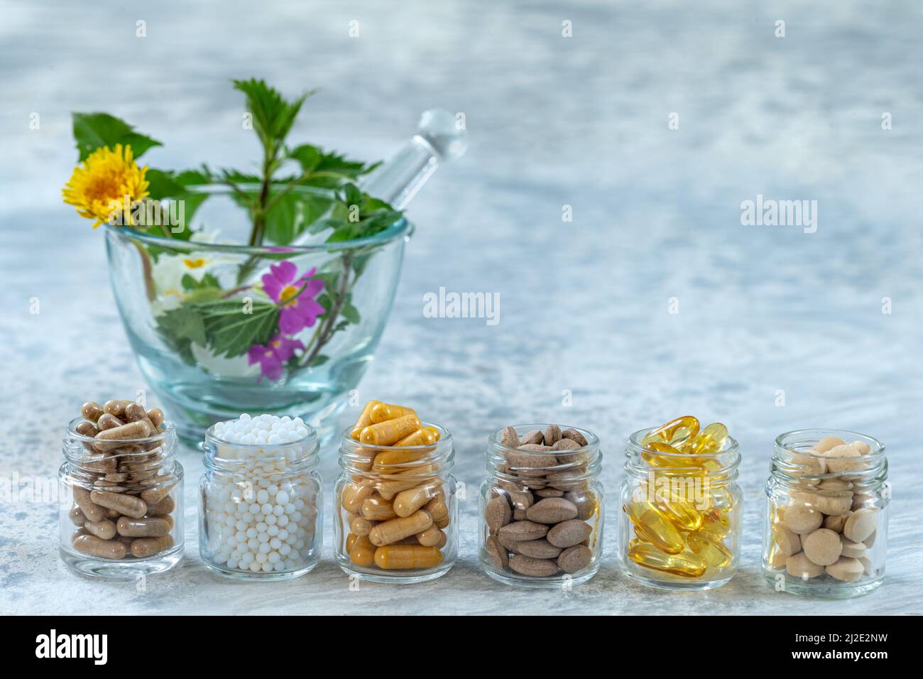 Bottiglia di pillole alimenti suplements medicina sana, farmaci trattamento salute additivi farmacia con ceramica mortaio bianco con piante fresche medicinali sullo sfondo Foto Stock