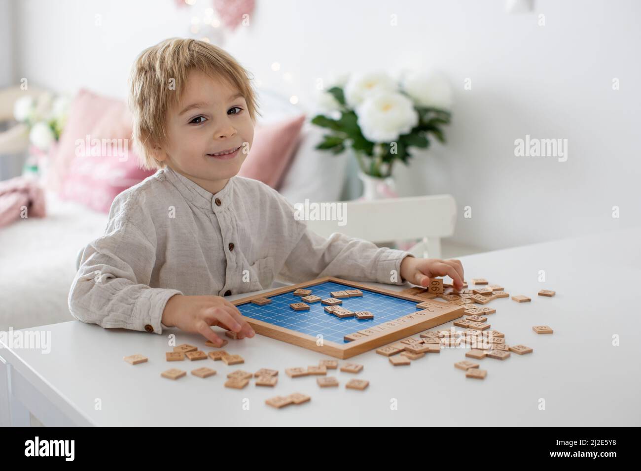 Bambino preschool, ragazzo biondo carino, giocando con numeri di legno a casa sul tavolo Foto Stock