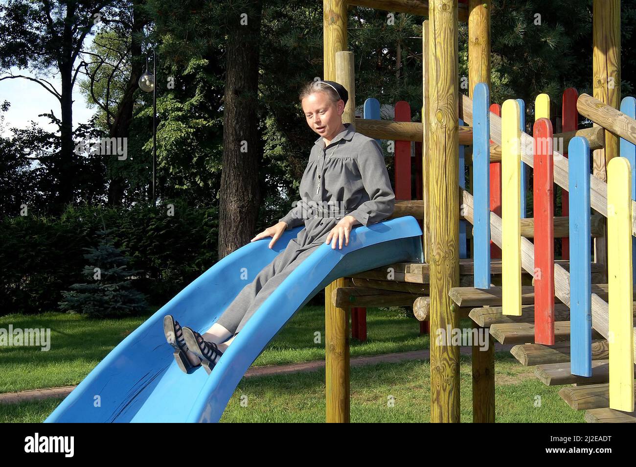 Augustów, Polonia, Polen, Polska, una suora su uno scivolo per bambini. Eine Nonne auf einer Kinderrutsche. Una monja en un tobogán para niños. 兒童滑梯上的修女。 Foto Stock