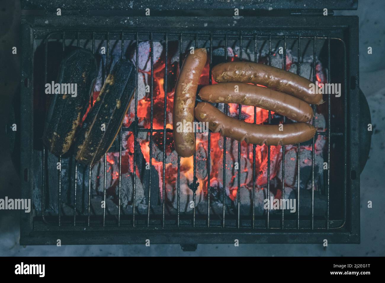Salsicce su una griglia, salsicce multiple visibili e pane bruciato su una griglia a carbone. Vista dall'alto di notte. Foto Stock