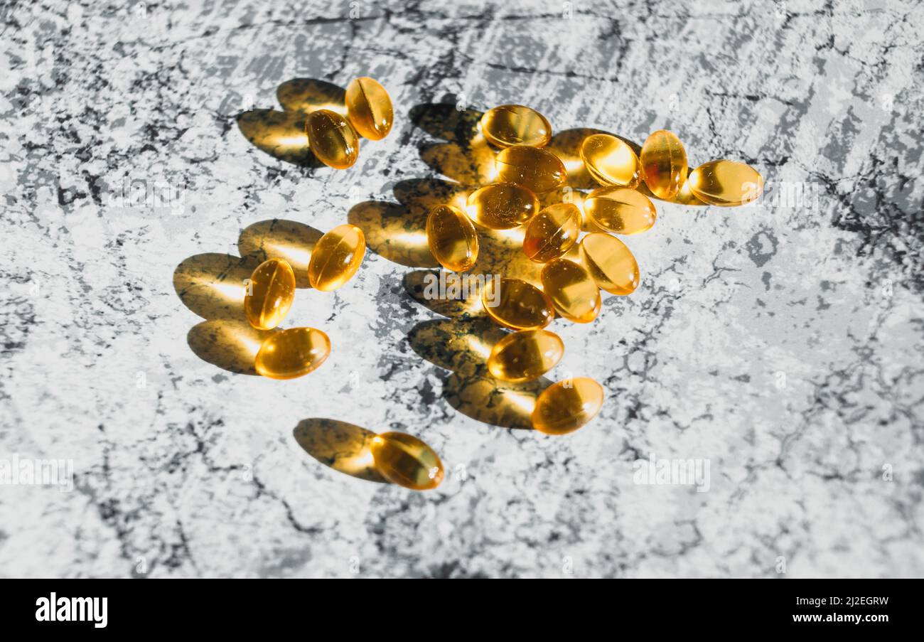 Capsule di fegato di merluzzo rivestite su sfondo decorativo grigio. Foto Stock