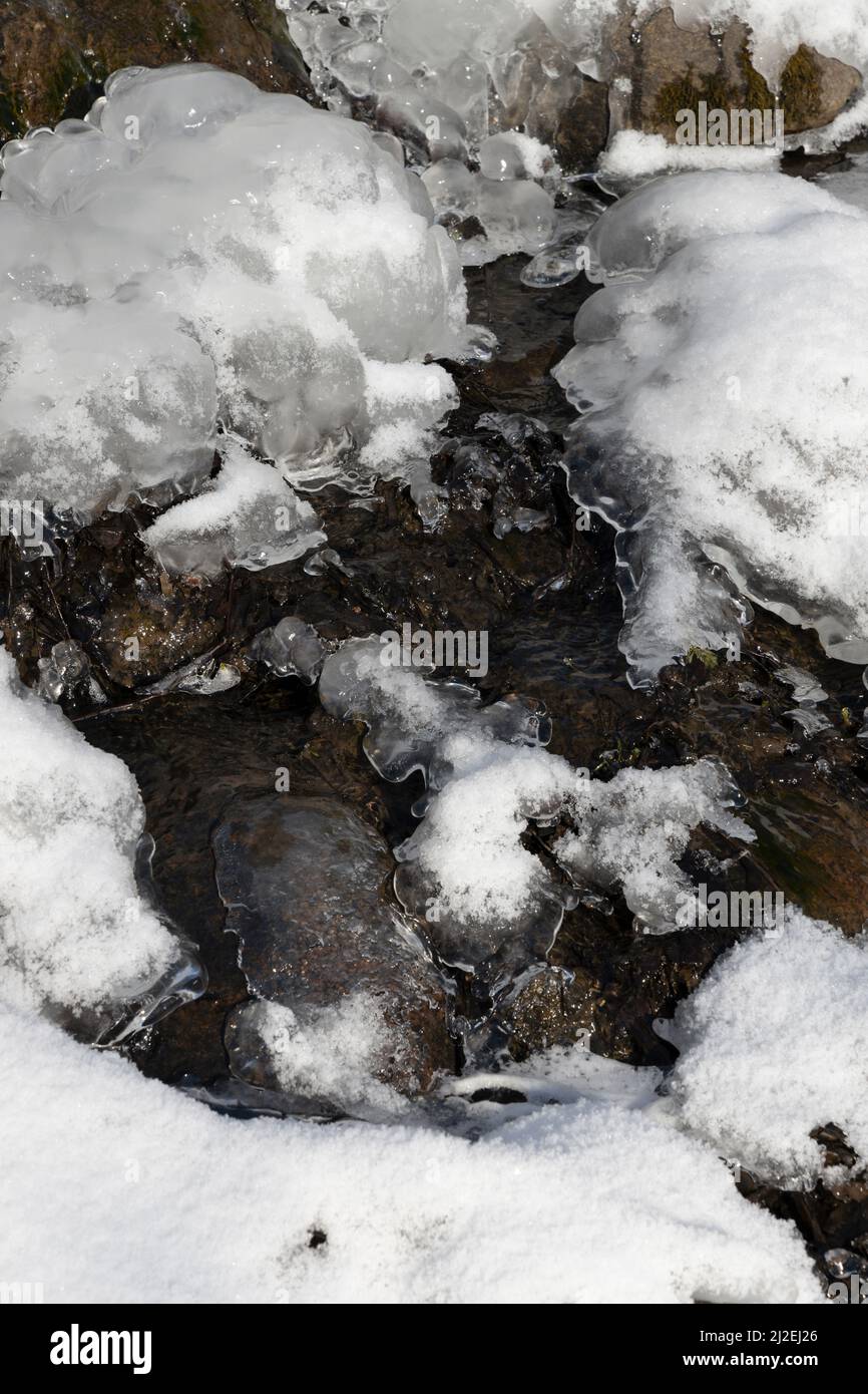 Il ghiaccio e la neve si sciolgono sotto il sole primaverile formando acque di sorgente Foto Stock