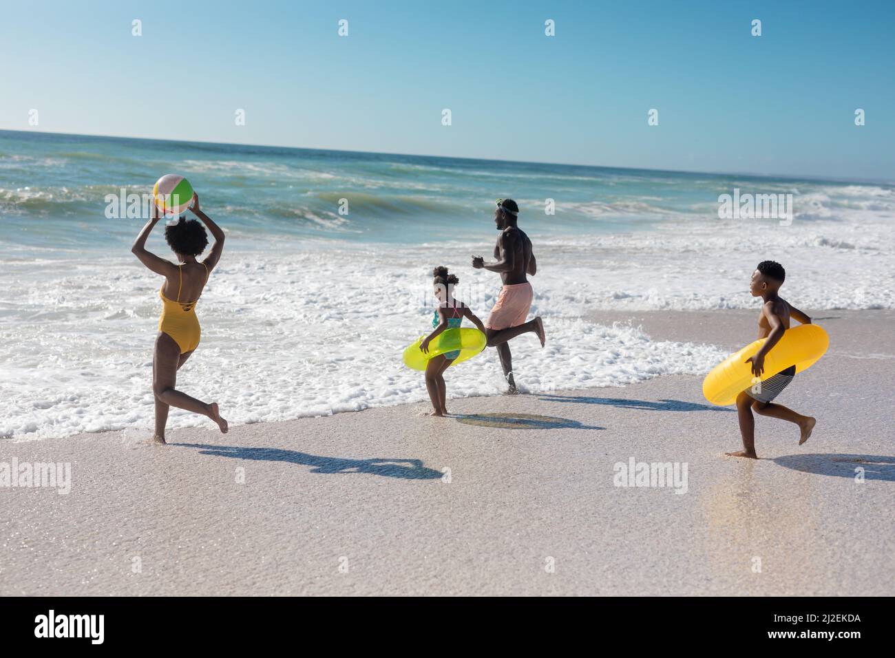 Genitori e bambini afroamericani che giocano insieme in spiaggia nella giornata di sole Foto Stock