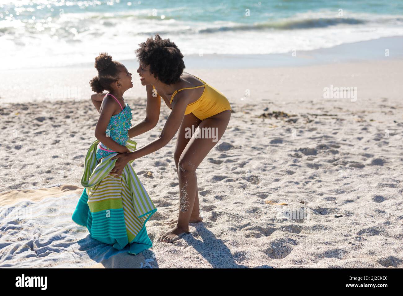 Tutta la lunghezza di madre e figlia afro-americana felice godendo giorno di sole alla spiaggia Foto Stock