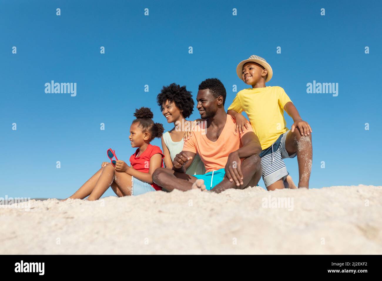 Felice famiglia afroamericana sulla sabbia sulla spiaggia contro il cielo blu chiaro con spazio copia Foto Stock Felice famiglia afroamericana sulla sabbia sulla spiaggia contro il cielo blu chiaro con spazio copia Foto Stock