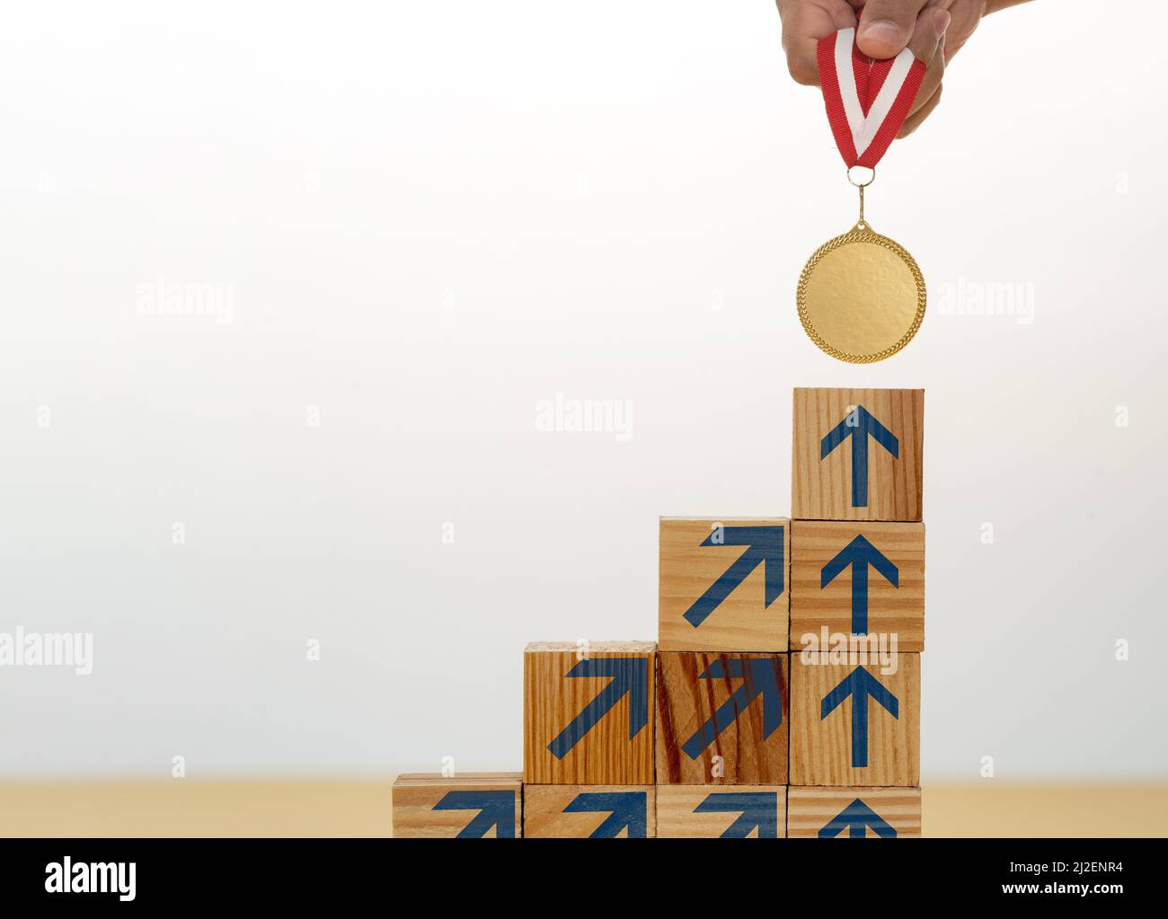 Scala step up fatta di blocchi di legno sulla medaglia d'oro superiore come simbolo di obiettivo ambizione motivazione sul successo. Foto Stock