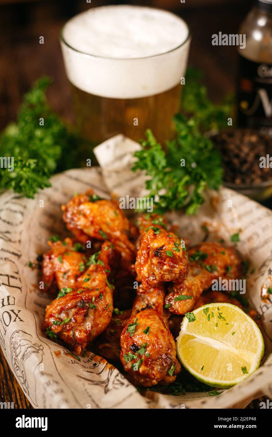 Porzione di bastoncini di pollo fritti in profondità e ricoperti di salsa calda (condita con). Servito con una metà di lime su carta artigianale. Foto Stock