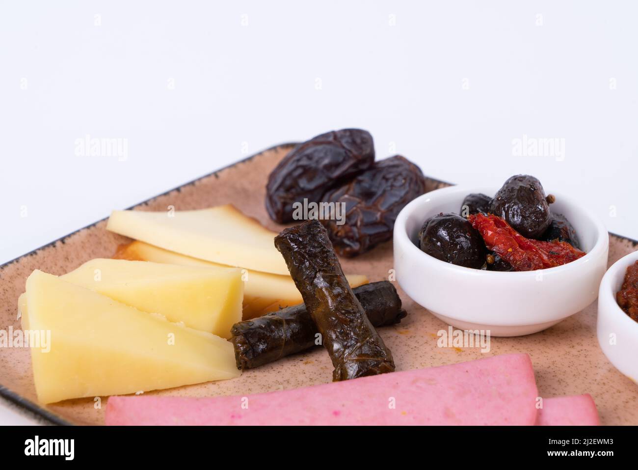 Vista ravvicinata di noci, olive, concentrato di pomodoro, fette di formaggio, impacco, prosciutto, albicocche secche, dattero e formaggio cheddar su fondo bianco isolato, oppos Foto Stock