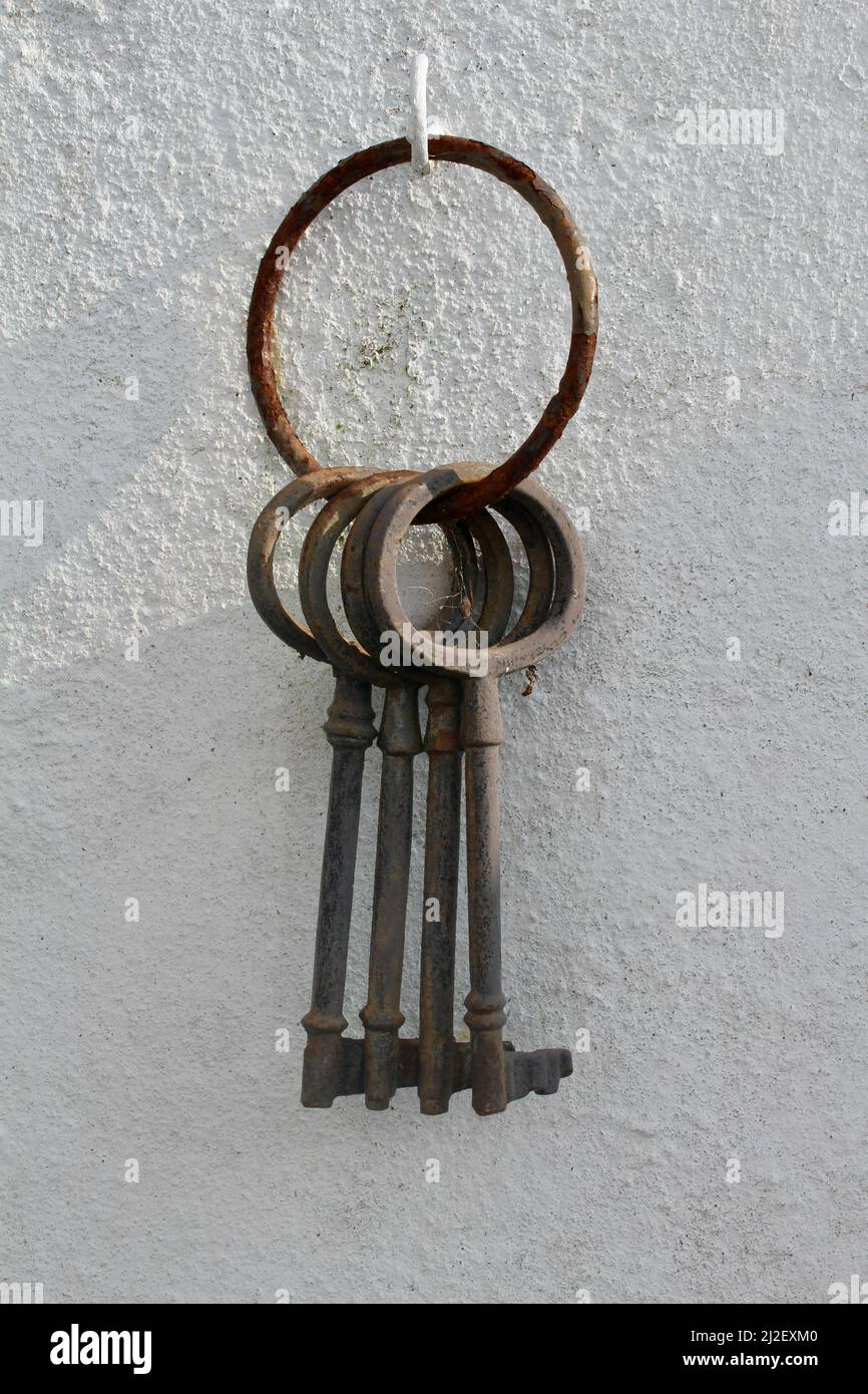 Vecchio mazzo di chiavi appese su una parete bianca Foto Stock