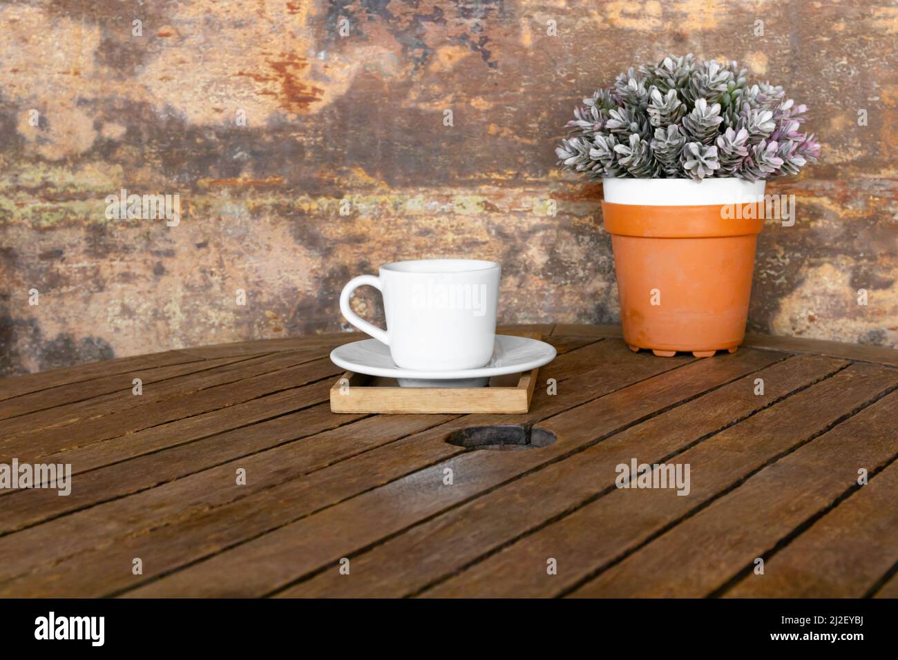 tazza di caffè bianca su tavola di legno vintage e vaso di fiori Foto Stock