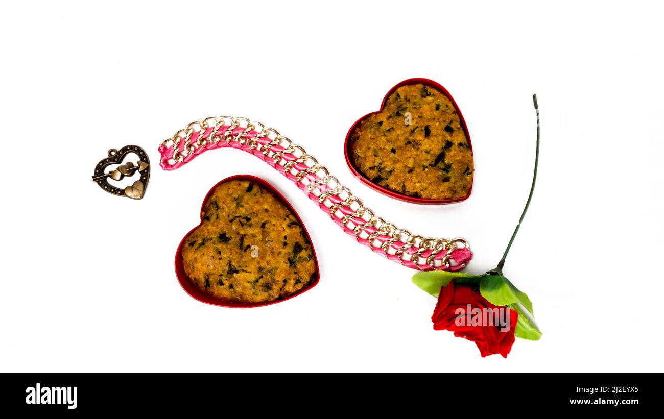 Forma del cuore Gujarati spuntini Muthiya in ciotola rossa con rosa rossa - alimento sano cucinato a vapore, salsa di Catsup di Ketchup, fondo bianco isolato piatto completo Foto Stock