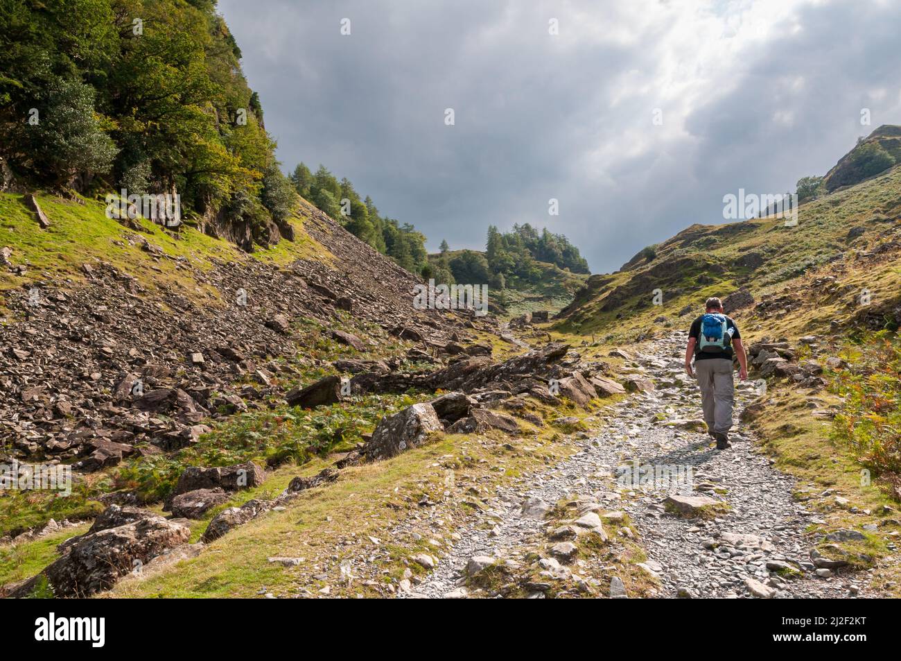 Un escursionista maschile sta camminando sul sentiero accidentato attraverso le Jaws di Borrowdale in direzione di Castle Crag nel Lake District, Cumbria, Inghilterra. La s Foto Stock