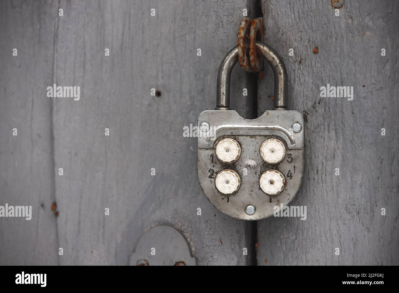 Vecchio lucchetto a combinazione appeso su porta di legno grigio grungy. Foto da vicino Foto Stock