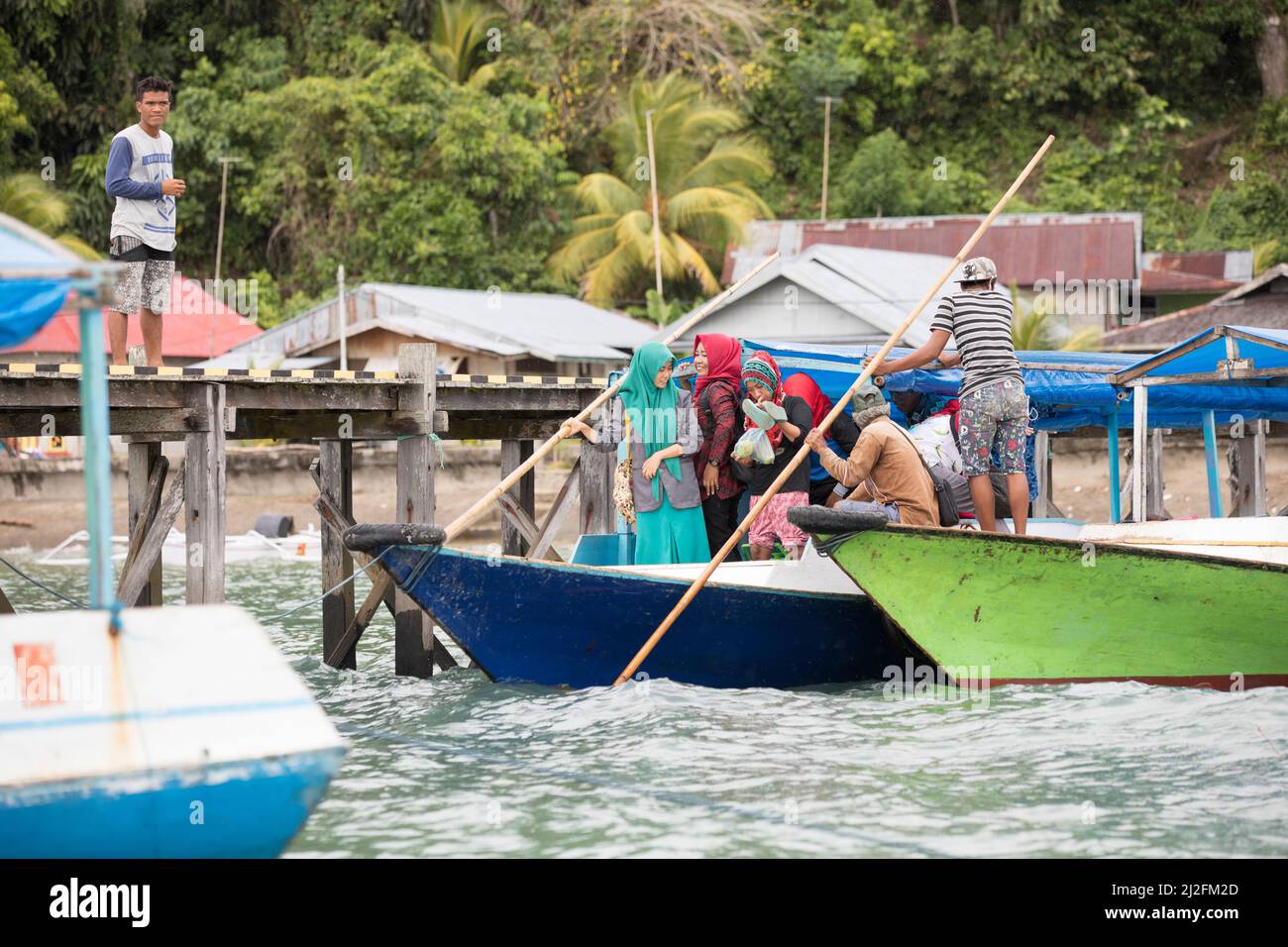 I traghetti passeggeri partono in acqua guidati da un barcaiolo con il personale di un piccolo villaggio di pescatori sull'isola di Karampuango, Indonesia. Foto Stock