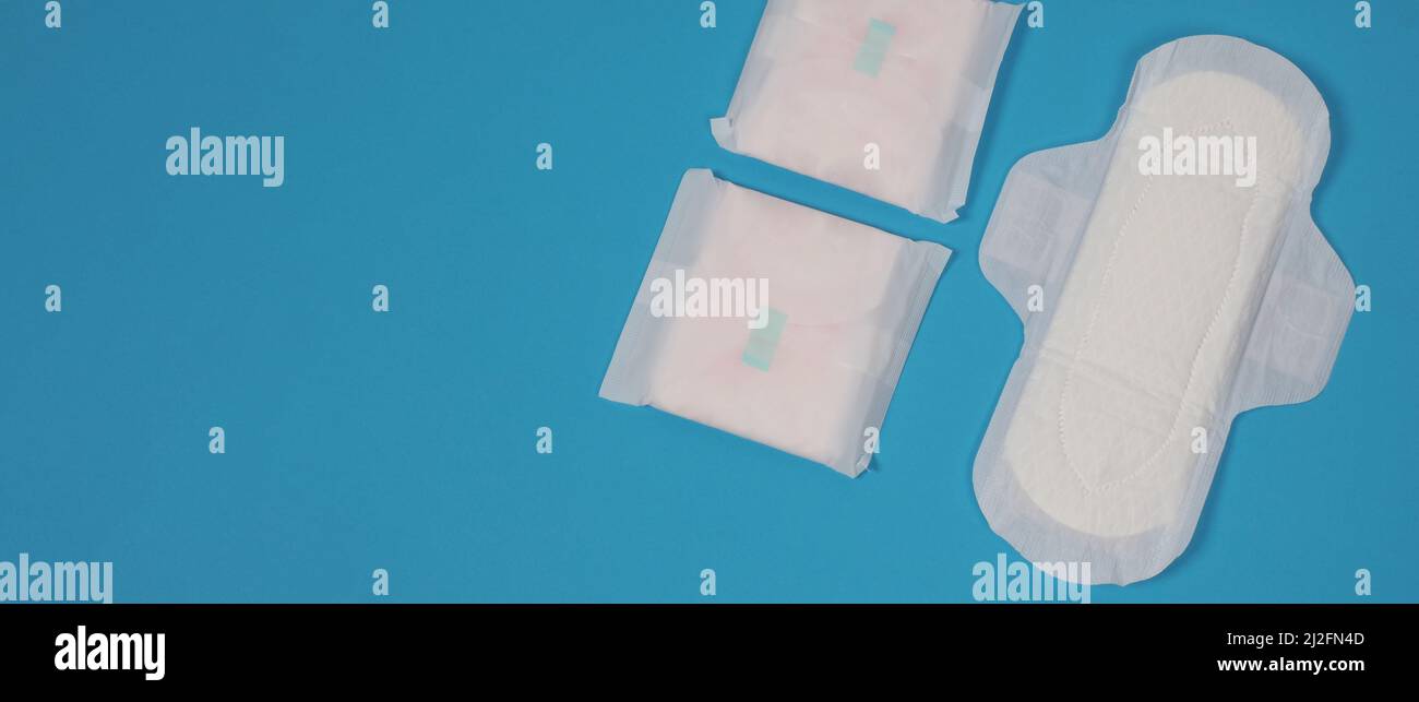 Assorbenti igienici donna su sfondo blu. Vista dall'alto. Tamponi assorbenti indossati dalle donne per assorbire il sangue mestruale. Comodi assorbenti igienici bianchi disposti Foto Stock