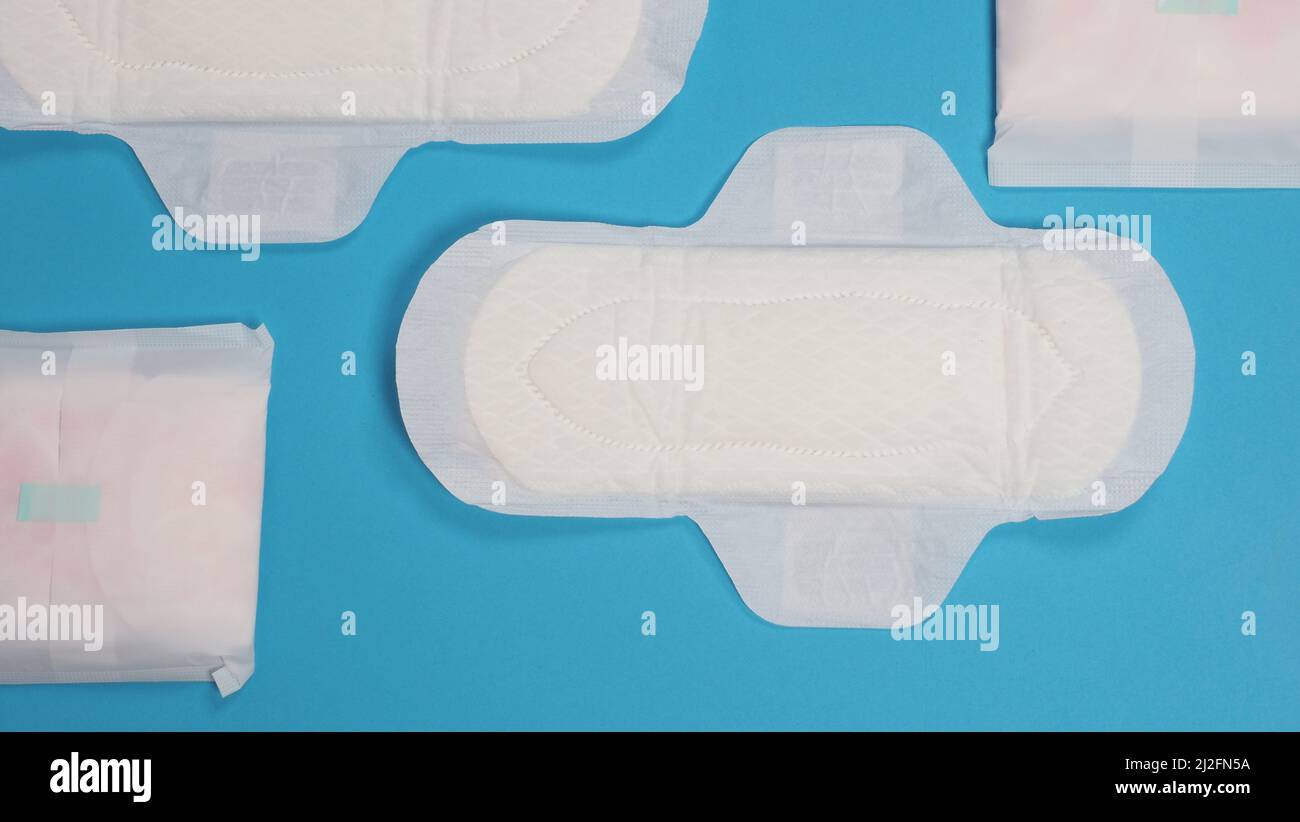 Assorbenti igienici donna su sfondo blu. Vista dall'alto. Tamponi assorbenti indossati dalle donne per assorbire il sangue mestruale. Comodi assorbenti igienici bianchi disposti Foto Stock