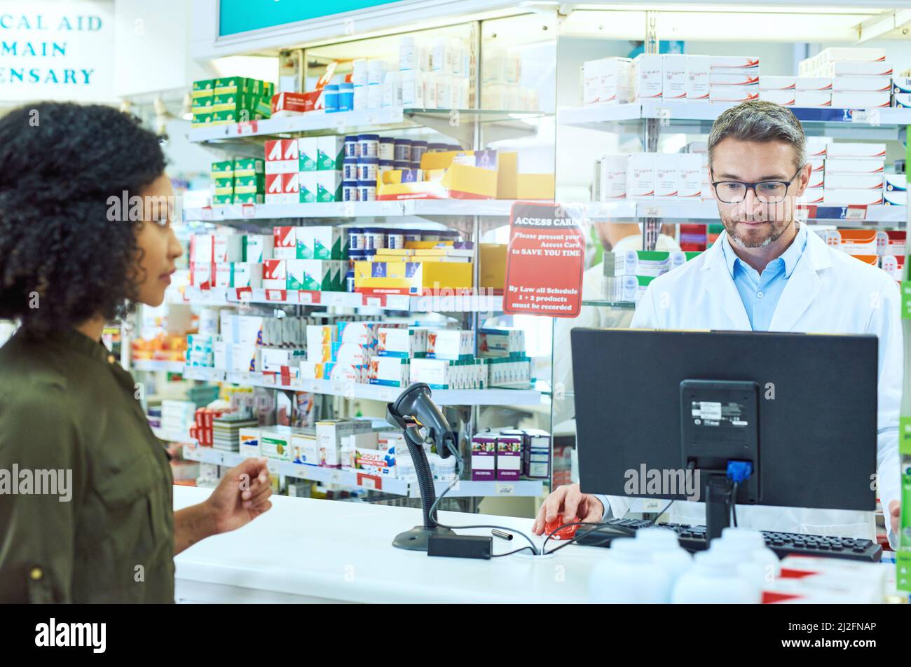 Check out. Scatto corto di un bel farmacista maschio maturo aiutando una cliente femminile in farmacia. Foto Stock