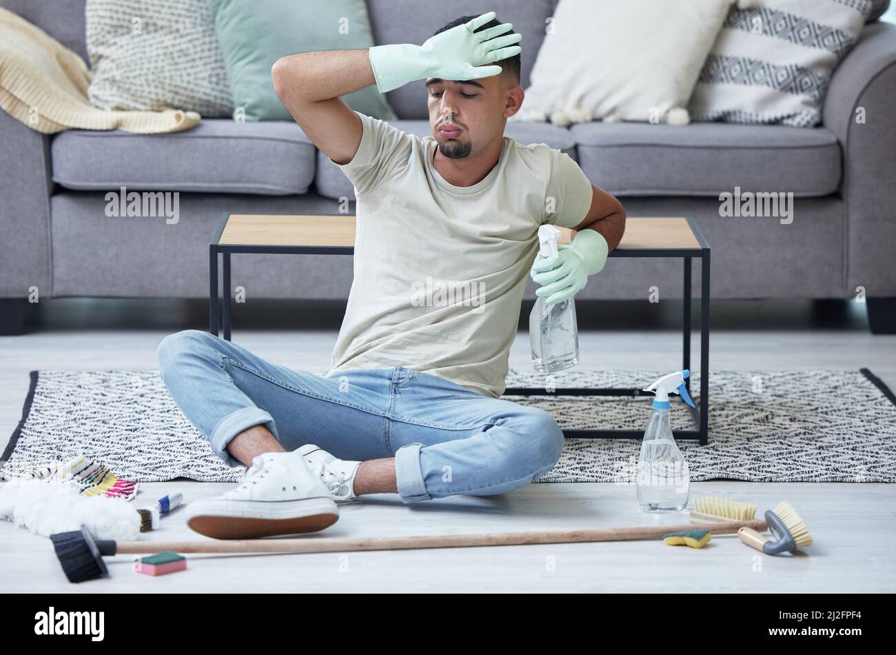 Niente inclinazione, solo pulizia. Scatto di un giovane uomo che prende una pausa dalle faccende a casa. Foto Stock