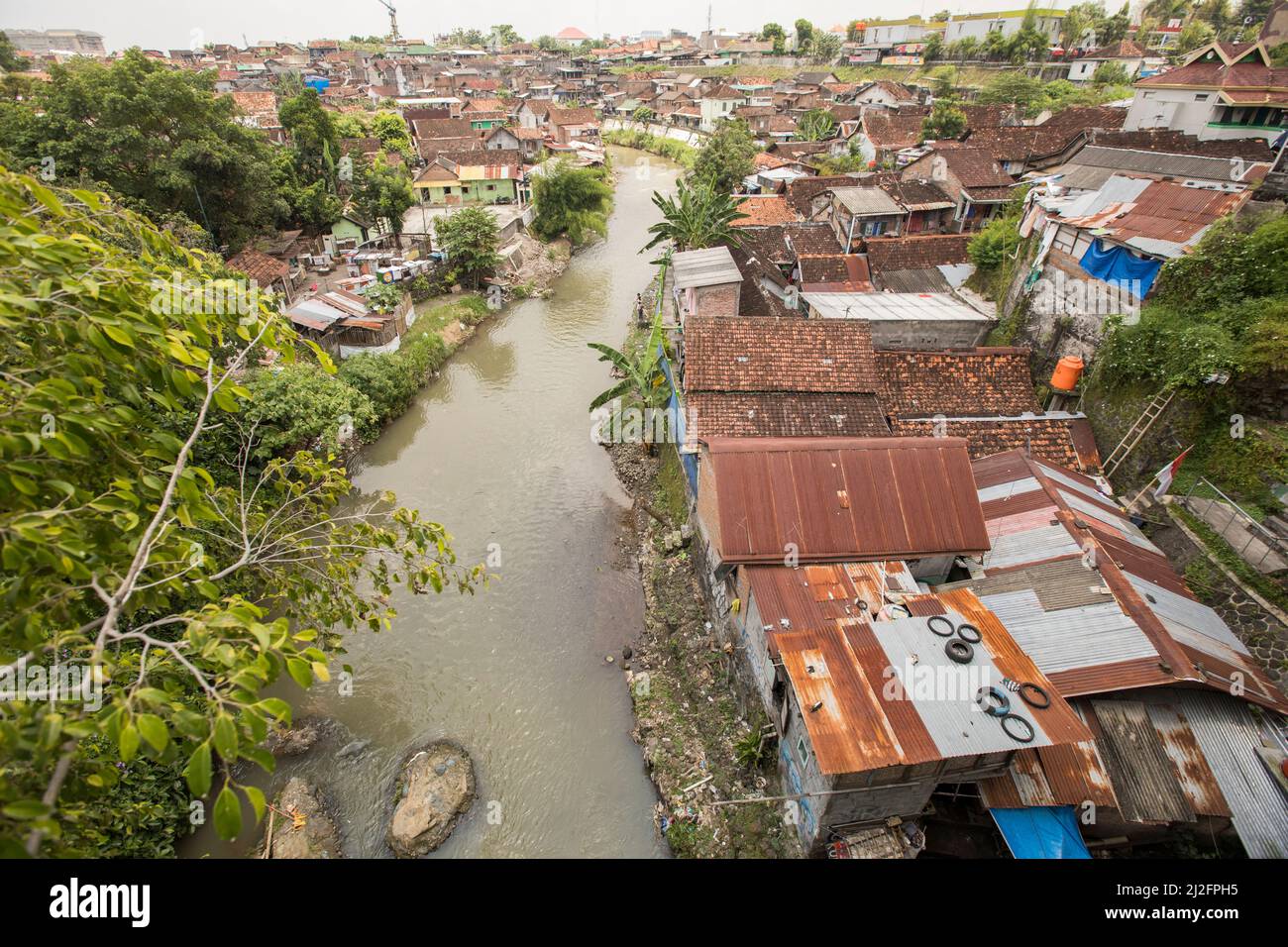 Affollate e colorate abitazioni di slum si trovano lungo un canale di drenaggio delle acque reflue a Yogyakarta (Jogjakarta), la seconda città più grande dell’Indonesia. Foto Stock