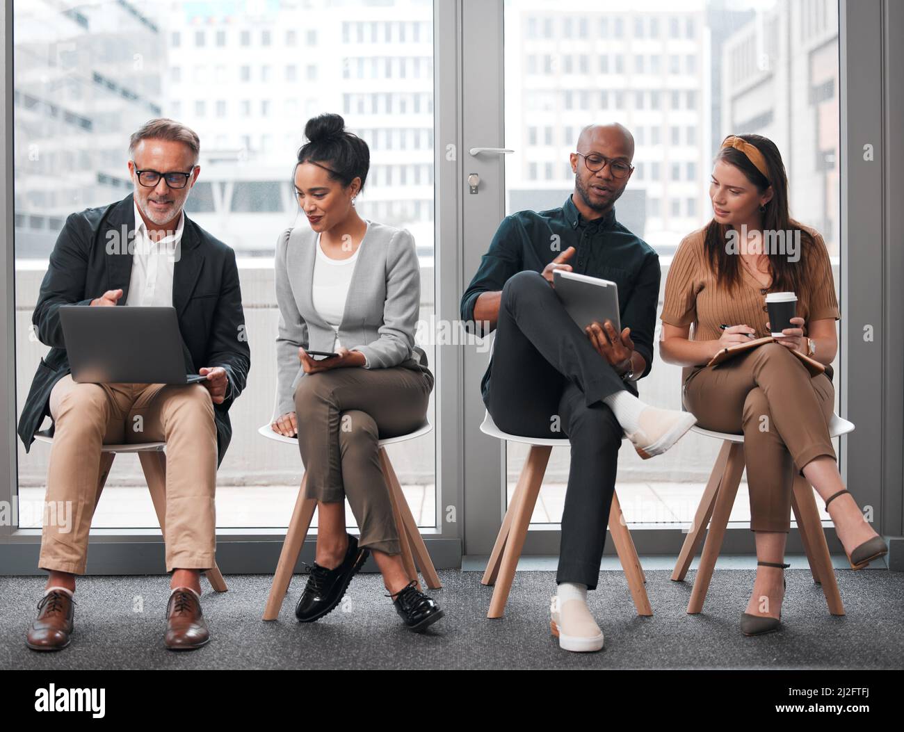 Scelte per il futuro. Girato di un gruppo di uomini d'affari che utilizzano i loro dispositivi elettronici su uno sfondo di vetro in città. Foto Stock