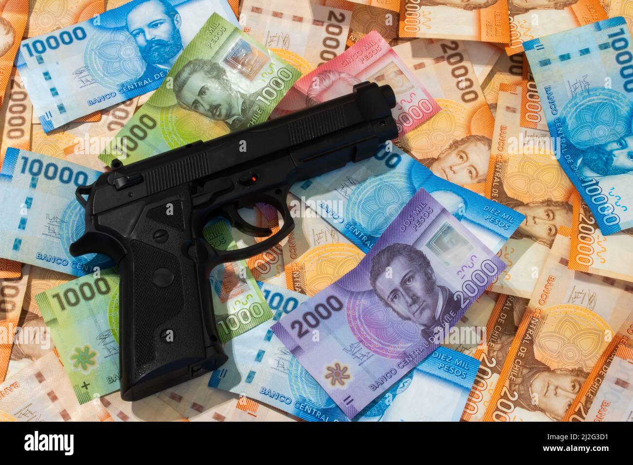 Pistola sopra le banconote cilene. Concetto di criminalità. Foto Stock