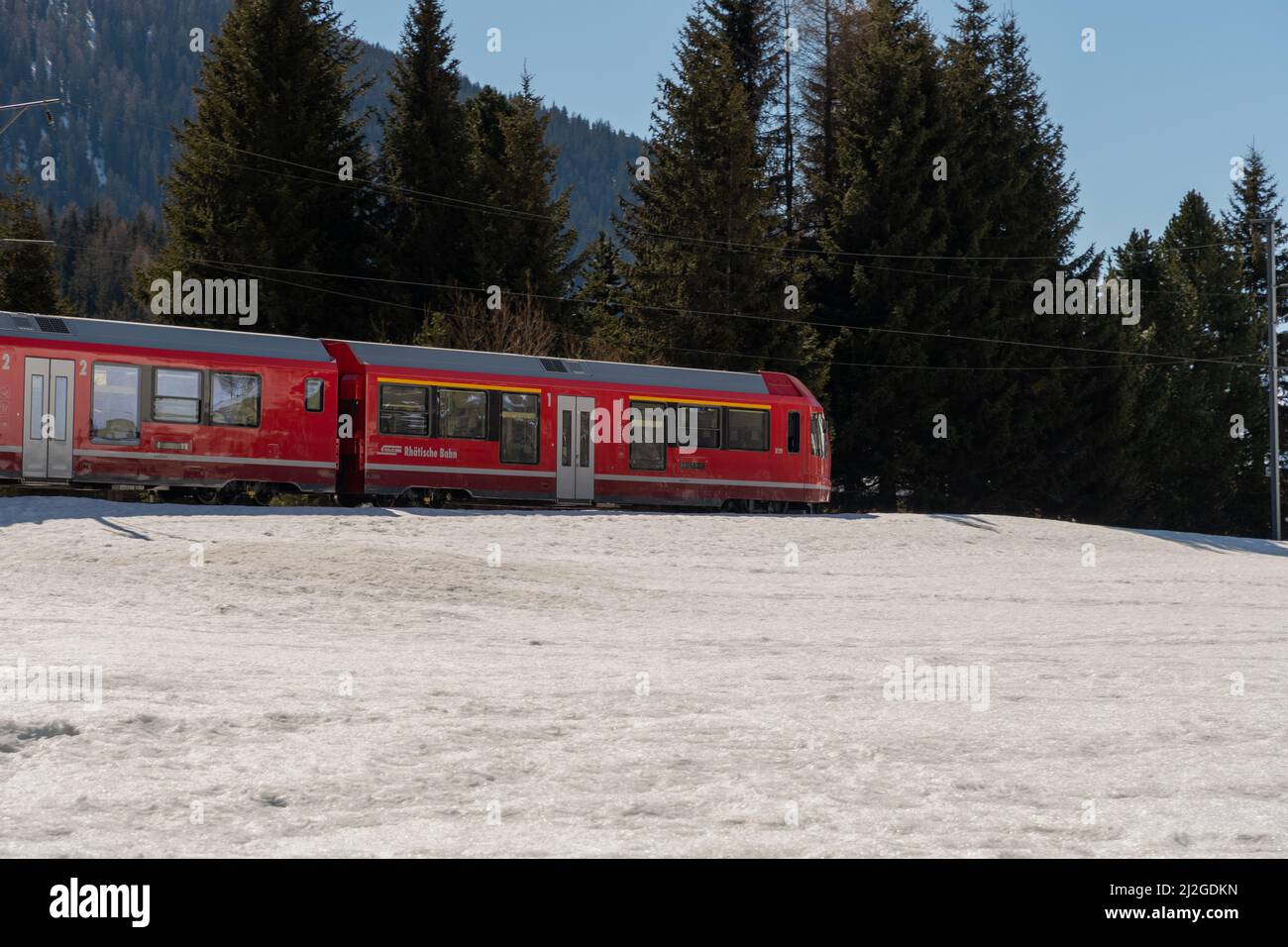 Davos, Svizzera, 23 marzo 2022 il treno locale passa attraverso un paesaggio invernale coperto di neve sulla strada per il centro della città Foto Stock