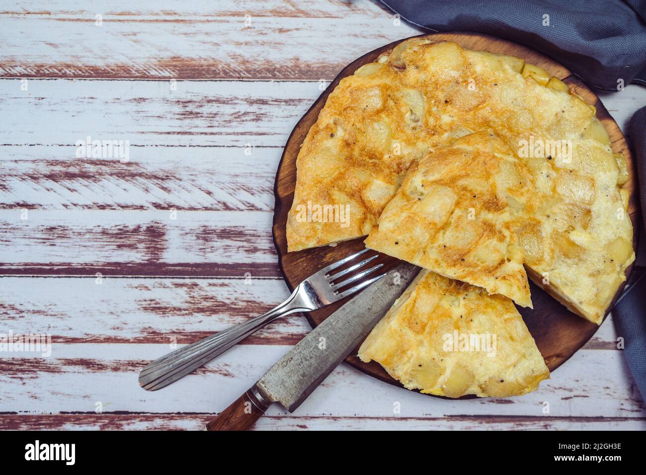 Vista dall'alto di un piatto con una frittata di patate spagnola tagliata in ottanta su un tavolo di legno. Spazio copia. Foto Stock