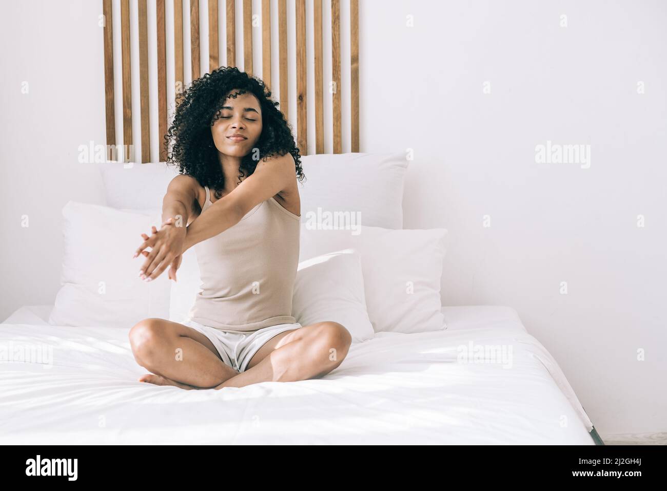 Giovane donna africana che si svegliava a letto al mattino e si allunga dopo il sonno. Foto Stock