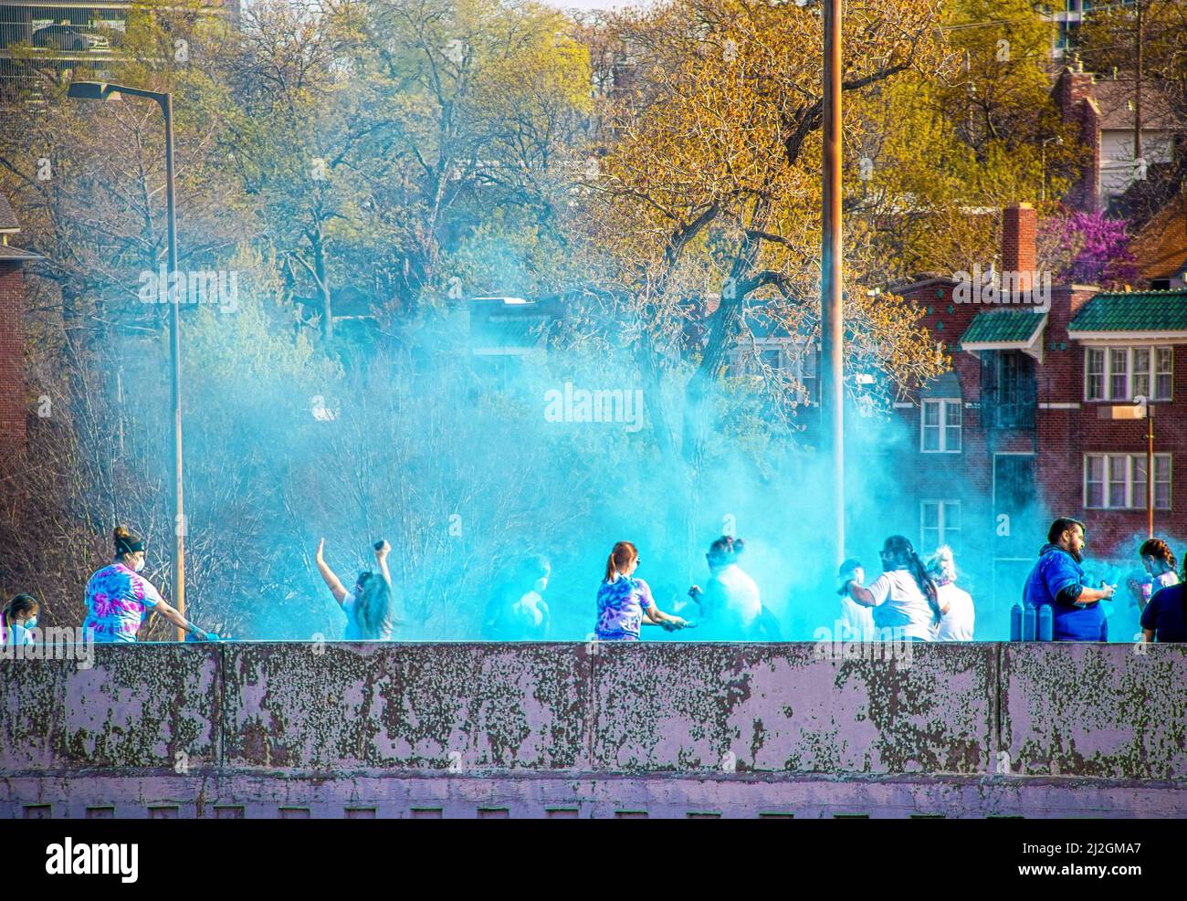 Aprile 6 2019 Tulsa USA - Holi - Color Run a Tulsa USA - i corridori sono schiacciati con polvere colorata sul ponte con case e alberi dietro di loro Foto Stock