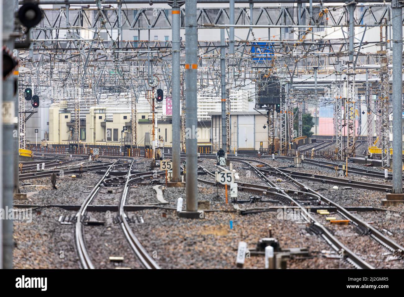 I binari del treno si incrociano sotto i cavi in alto in un cantiere ferroviario vuoto Foto Stock