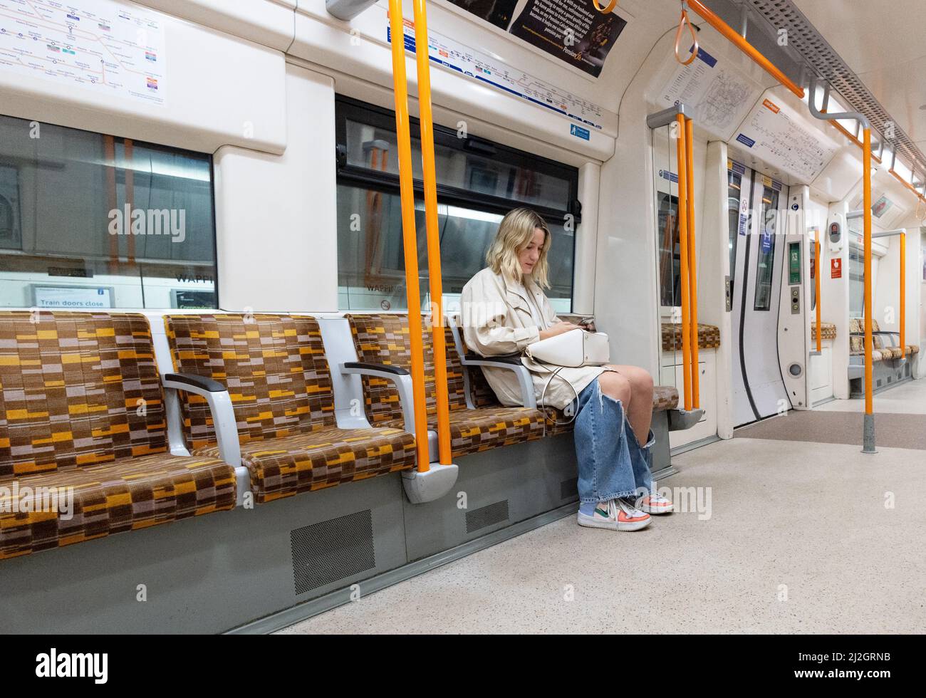 Donne che viaggiano in treno; una donna che viaggia da sola seduta in una carrozza interna, London Overground, TFL, London UK Foto Stock