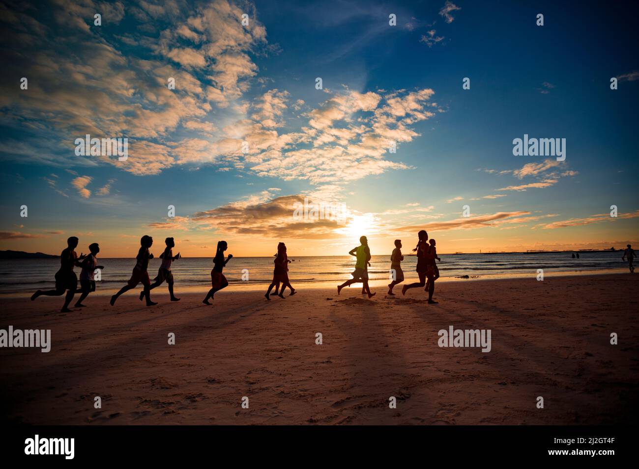 Attività di gruppo persone che corrono al tramonto sulla spiaggia di sabbia Foto Stock