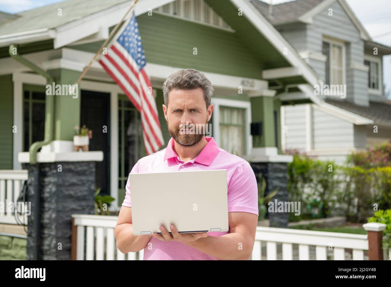 uomo bearded realtor che compra casa in linea sul laptop, proprietà Foto Stock