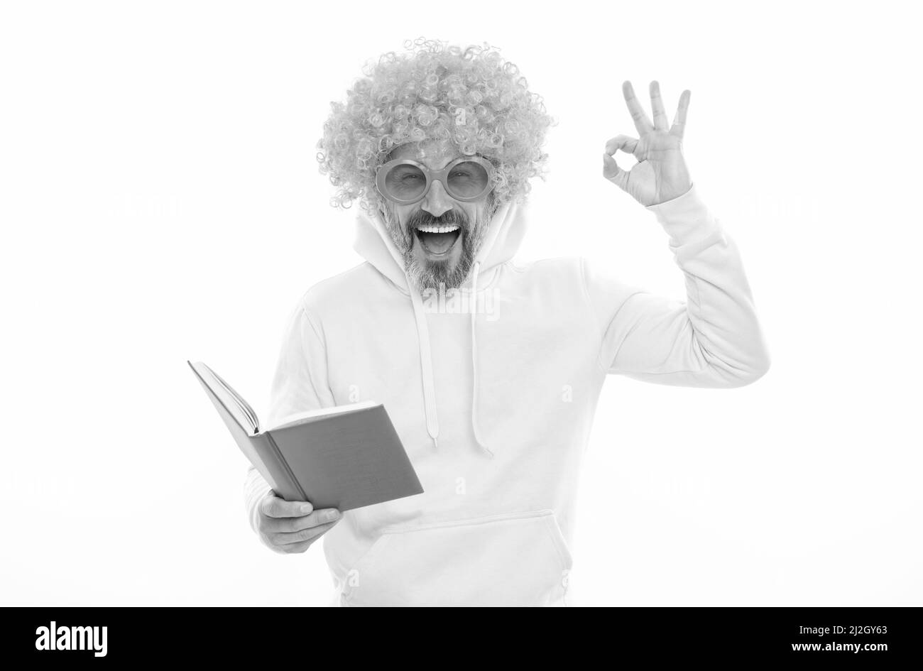 Uomo felice in funky show wig OK segno gesto lettura libro scuola in geek occhiali da sole, educazione Foto Stock