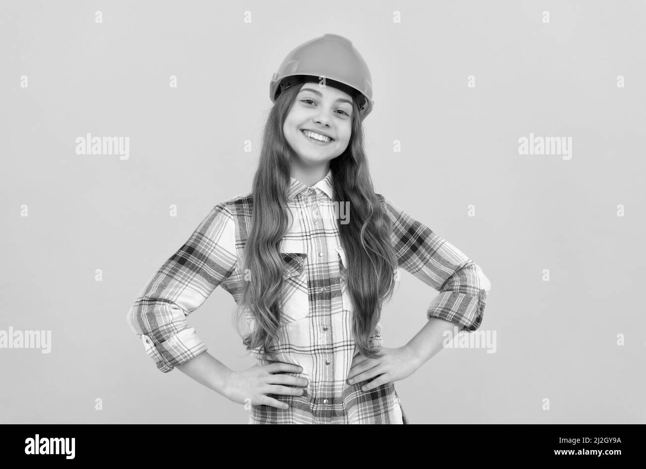 felice ragazza teen in casco e camicia a scacchi, costruttore Foto Stock