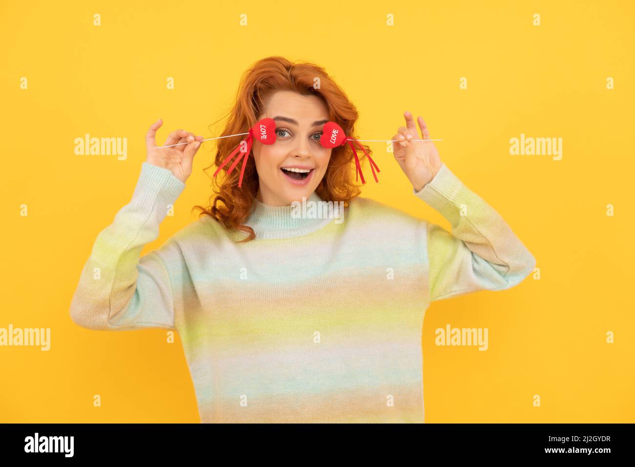 felice ragazza rossa divertente con cuore rosso bastoni su sfondo giallo. febbraio 14 Foto Stock
